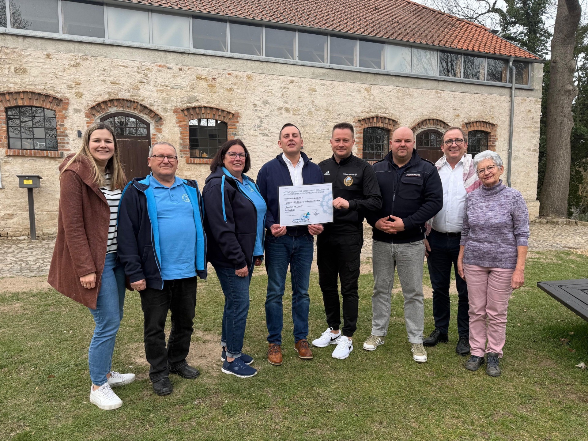 En la imagen aparecen el alcalde Ronny Küster (4.º por la izquierda) y el presidente del distrito Markus Bauer (2.º por la derecha) durante la entrega del cheque.