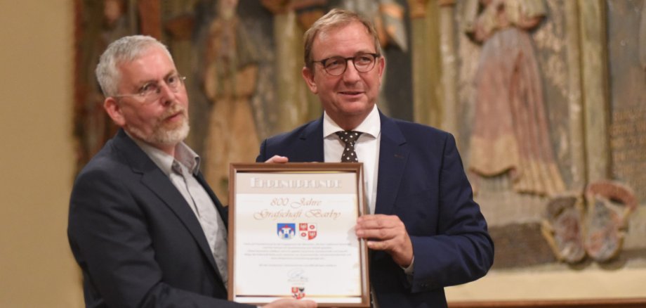 En la imagen aparecen el alcalde de Barbie, el Dr. Jörn Weinert (izq.), y el presidente del distrito de Salzland, Markus Bauer, durante la entrega del certificado de honor del distrito de Salzland. En la imagen aparecen el alcalde de Barbie, el Dr. Jörn Weinert (izq.), y el presidente del distrito de Salzland, Markus Bauer, durante la entrega del certificado de honor del distrito de Salzland.