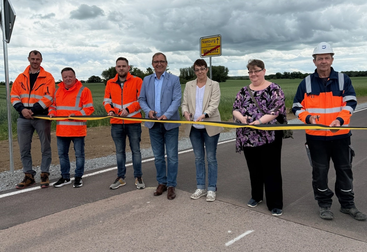 El administrador del distrito, Markus Bauer (4º por la izquierda), y la alcaldesa de Nienburg, Susann Falke (5ª por la izquierda), en la inauguración oficial de la carretera comarcal 2101, cerca de Wedlitz. También se puede ver a otras personas implicadas en la renovación.