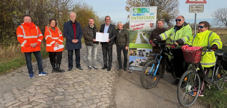 De gauche à droite : le chef de service Tilo Wechselberger, Jana Elbe, l'ingénieur Ludwig Koslowski, le maire de la communauté de communes Michael Stöhr, le Landrat Markus Bauer, le maire d'Egeln Reinhard Luckner et le maire adjoint de Hakeborn Dirk Bartsch ainsi que deux cyclistes sur la route départementale qui doit être transformée en piste cyclable d'ici 2027. Source de l'image : Marko Jeschor / Service de presse du Salzlandkreis De gauche à droite : le chef de service Tilo Wechselberger, Jana Elbe, l'ingénieur Ludwig Koslowski, le maire de la communauté de communes Michael Stöhr, le Landrat Markus Bauer, le maire d'Egeln Reinhard Luckner et le maire adjoint de Hakeborn Dirk Bartsch ainsi que deux cyclistes sur la route départementale qui doit être transformée en piste cyclable d'ici 2027. Source de l'image : Marko Jeschor / Service de presse du Salzlandkreis