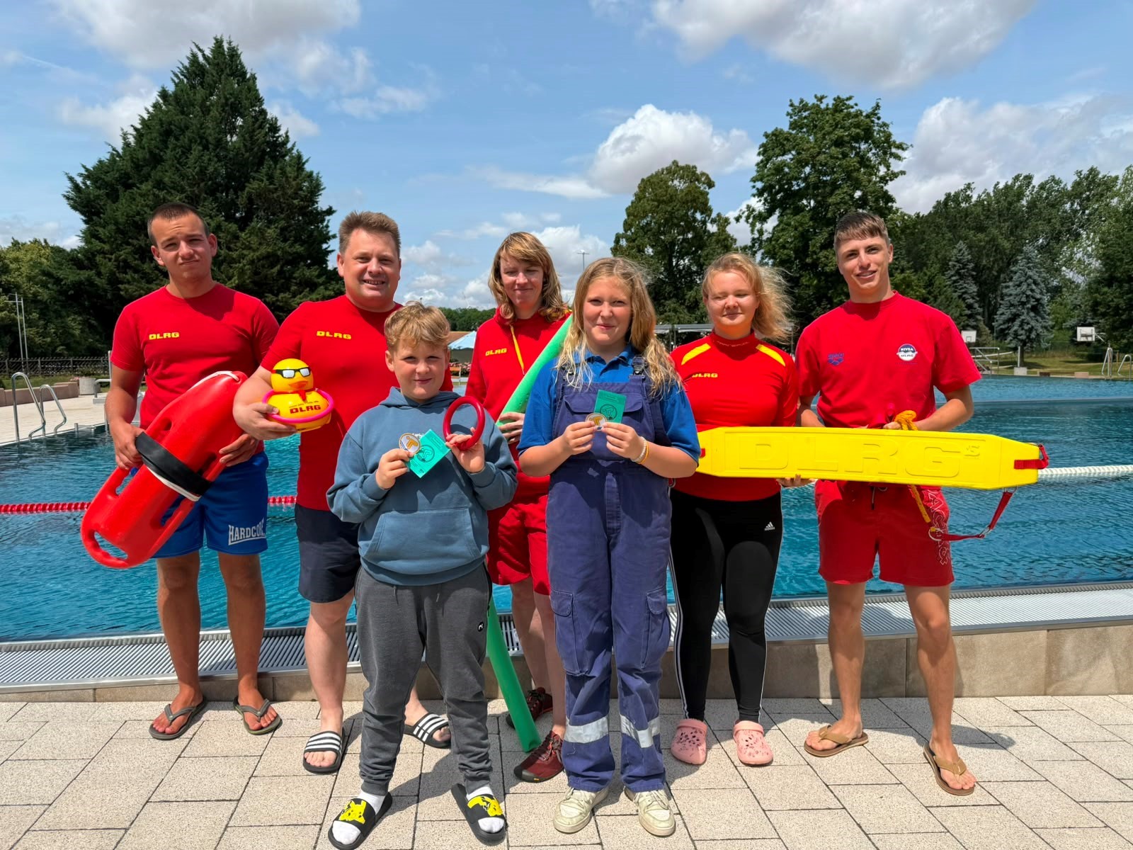 La photo montre des membres de la section locale de la DLRG de Bernburg ainsi que des enfants qui ont obtenu leur brevet de natation lors du premier « dimanche des hippocampes » à la piscine en plein air d'Alsleben.