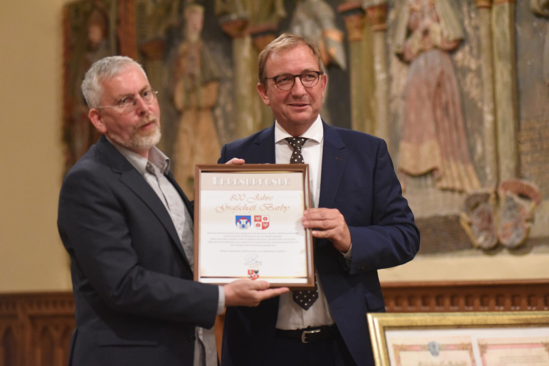 Das Bild zeigt Barbys Bürgermeister Dr. Jörn Weinert (l.) und Landrat Markus Bauer bei der Übergabe der Ehrenurkunde des Salzlandkreises.