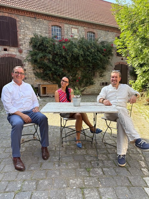 Landrat Markus Bauer (l.) sitzt gemeinsam mit Marlen und Kai Luther auf dem Hof des Lutherhofs in Drohndorf bei Aschersleben.