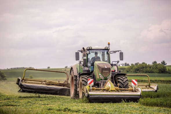 Traktor mit Mähkombination beim Grasmähen